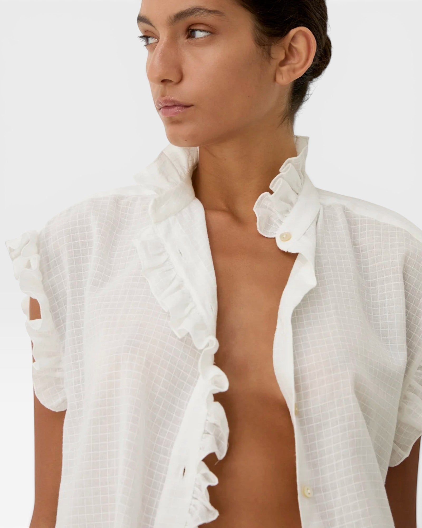 JONES + CO white organic cotton voile sleeveless blouse with tone-on-tone checkered pattern and ruffled trim.