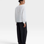 JONES + CO white organic cotton voile blouse with voluminous sleeves, gathered cuffs, deep V-neck, and mother-of-pearl buttons.