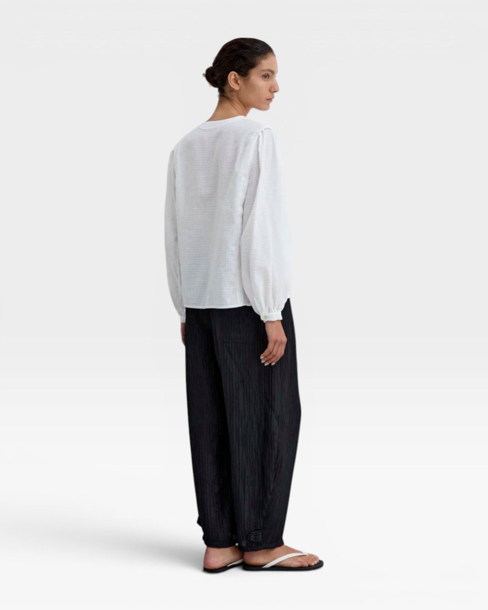 JONES + CO white organic cotton voile blouse with voluminous sleeves, gathered cuffs, deep V-neck, and mother-of-pearl buttons.