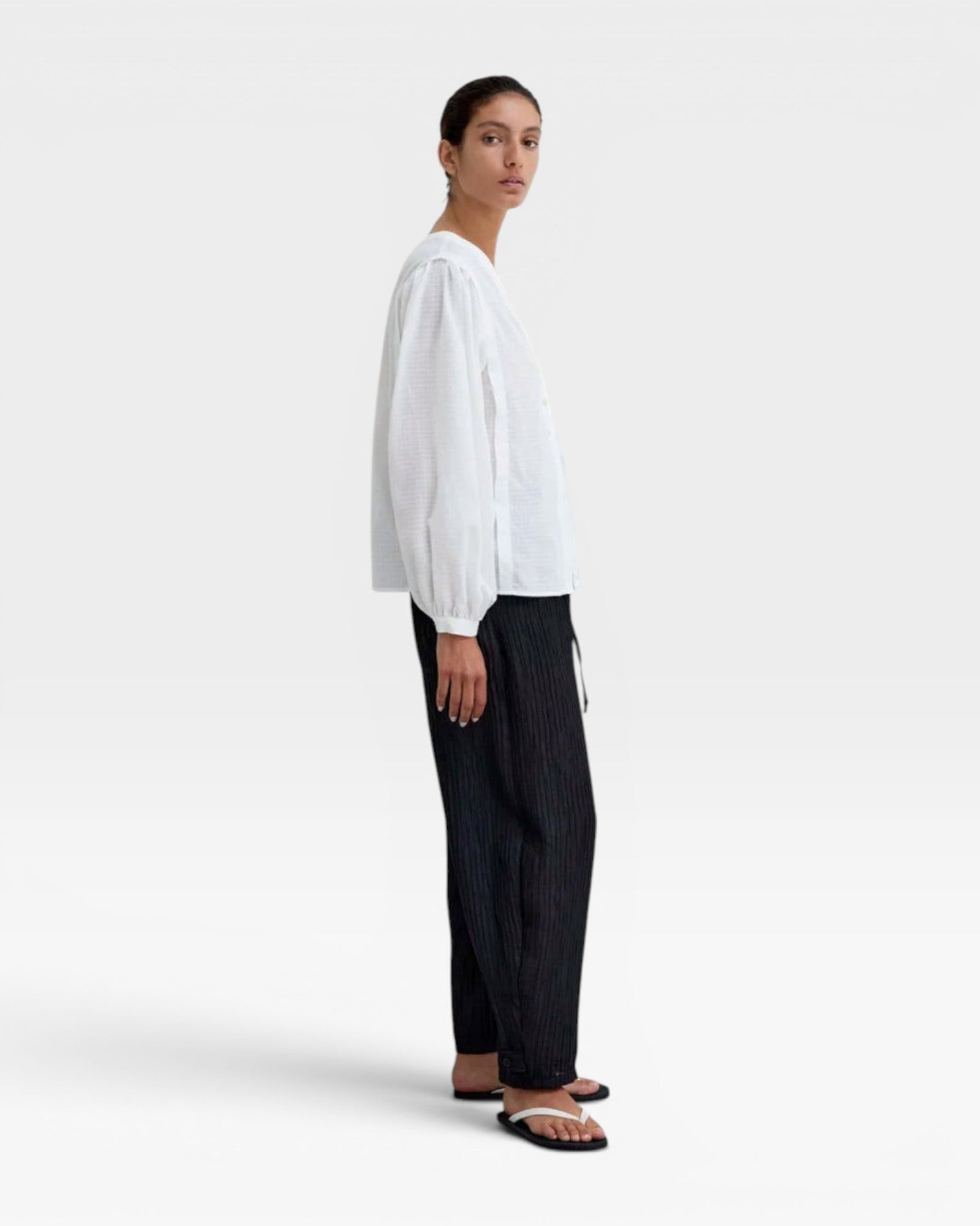 JONES + CO white organic cotton voile blouse with gathered cuffs and deep V-neckline, featuring a subtle checkered pattern.