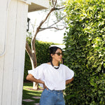 JONES + CO white cotton Coco shirt with boat neckline and dolman sleeves, worn by a woman outdoors.