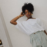 JONES + CO white cotton Coco Shirt with boat neckline and dolman sleeves, gathered hem, worn by a woman.
