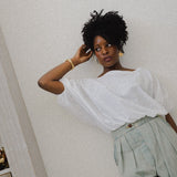 JONES + CO white cotton Coco Shirt with boat neckline and dolman sleeves, gathered hem, worn by a woman.