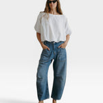 JONES + CO white cotton Coco shirt with boat neckline and dolman sleeves, gathered hem. Model wears sunglasses.