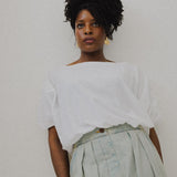 JONES + CO white Coco Shirt with boat neckline and dolman sleeves, paired with light wash pleated denim.