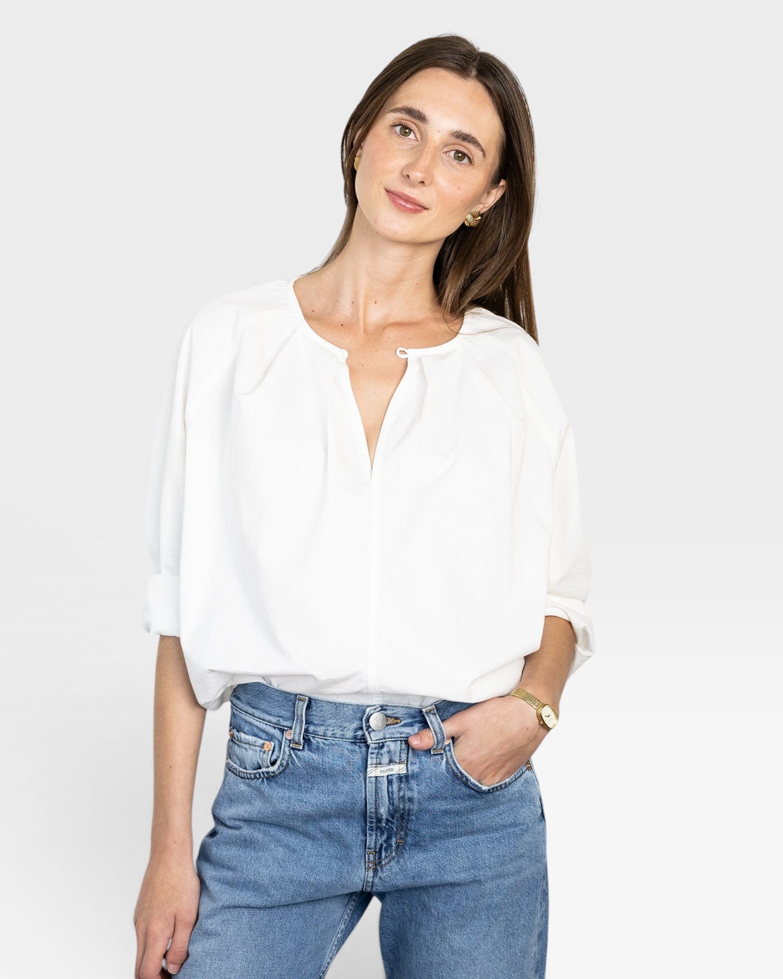 JONES + CO white cotton Julienne long sleeve top with keyhole neckline and pleating. Model wears jeans.