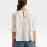 JONES + CO white 100% Pima cotton lawn Sol top with crochet lace trim, puff sleeves, and tiered silhouette.