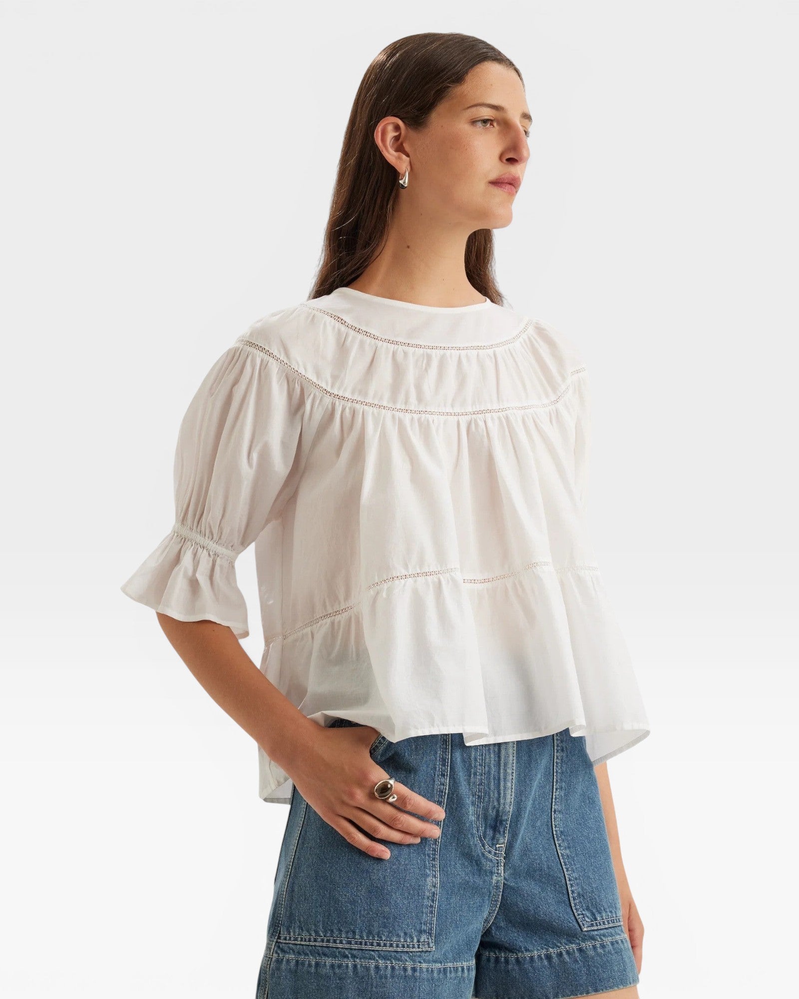 JONES + CO white 100% Pima cotton lawn Sol top with boat neck, crochet trim, puff sleeves, and ruffle cuffs.