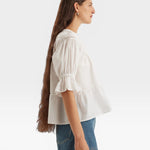 JONES + CO white 100% Pima cotton lawn Sol top with boat neck, crochet trim, puff sleeves, and ruffle cuffs.