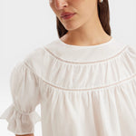 JONES + CO white 100% Pima cotton lawn Sol top with crochet lace trim, boat neck, puff sleeves, and ruffle cuffs.