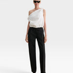 Model wearing JONES + CO white one-shoulder Farfalla top in Italian Foam fabric with draped silhouette and drawstring.