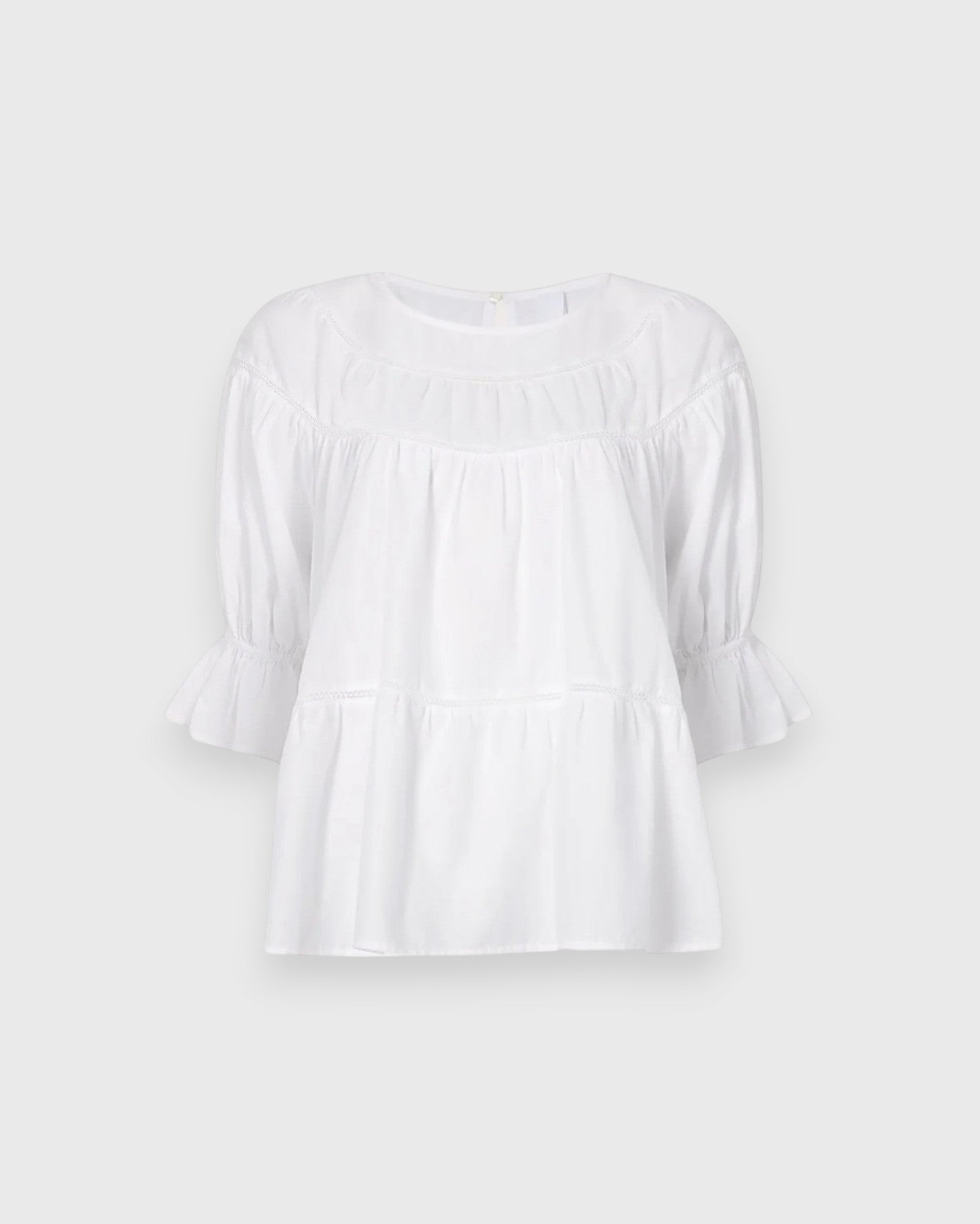 JONES + CO white 100% Pima cotton lawn Sol Top blouse with boat neck, crochet trim, and puff sleeves with ruffled cuffs.