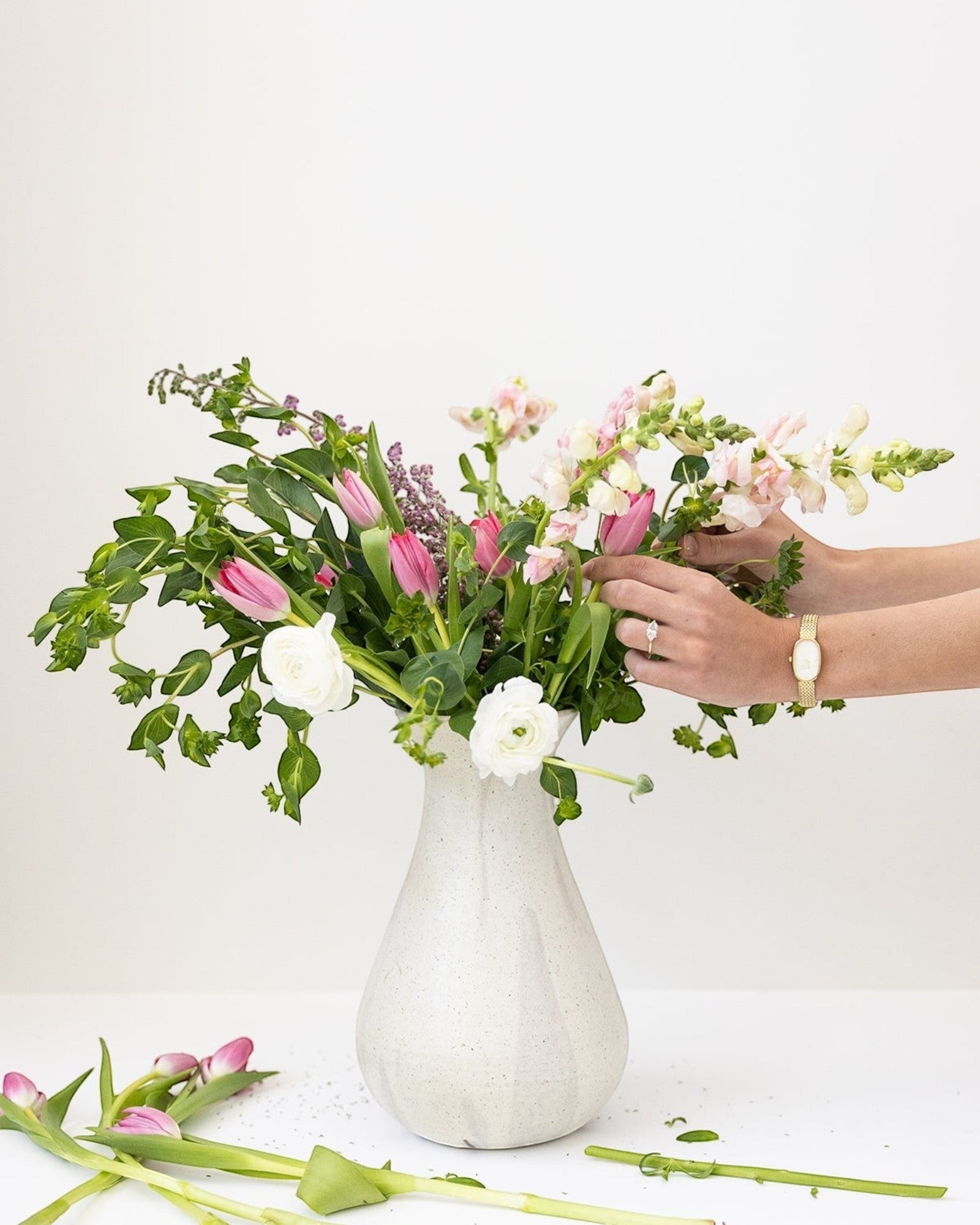 JONES + CO white speckled ceramic bulb vase with a bouquet of pink and white flowers.