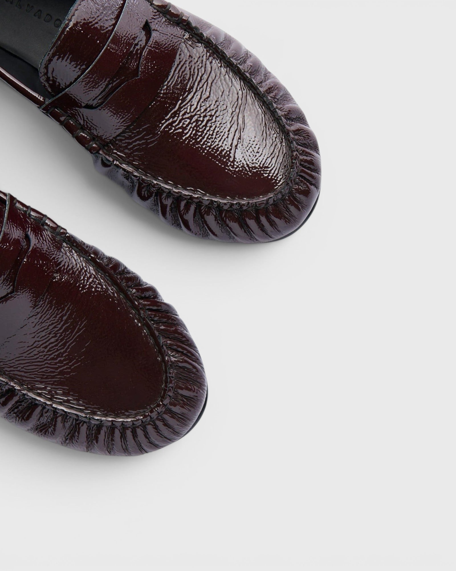 JONES + CO Sydney wine crinkle patent leather penny loafers with ruched detailing, top-down view.