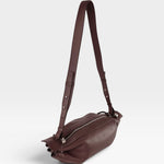 JONES + CO Bon-Bon M wine-colored soft calf leather crossbody bag with pleated ends and silver-tone metal hardware.