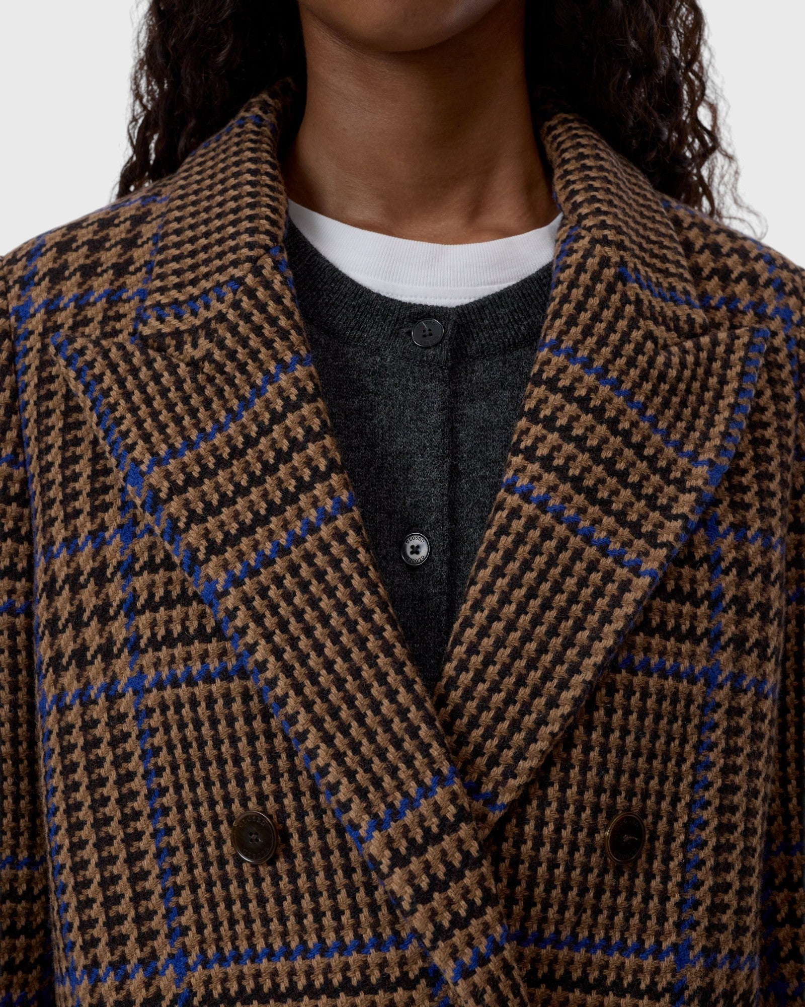 JONES + CO double-breasted wool-blend blazer in sand beige with a blue and black oversized check pattern and wide lapels.
