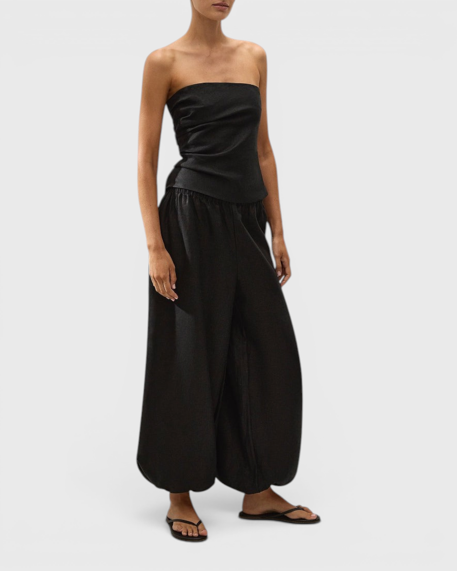 JONES + CO Alzira strapless black linen top with asymmetric front pleats and back tie detail on a model