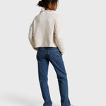Model wearing JONES + CO Arden mock neck sweatshirt in sugar French terry with blue denim jeans, back view