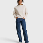 Model wearing JONES + CO Arden mock neck sweatshirt in sugar cream French terry with blue denim jeans