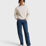 Model wearing JONES + CO Arden mock neck sweatshirt in sugar cream French terry with blue denim jeans
