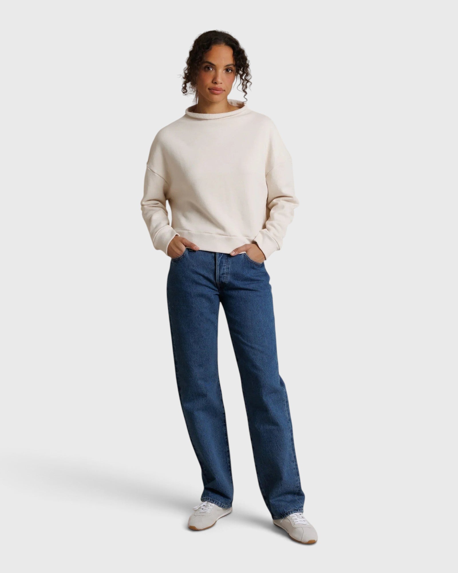 Model wearing JONES + CO Arden mock neck sweatshirt in sugar cream French terry with blue denim jeans