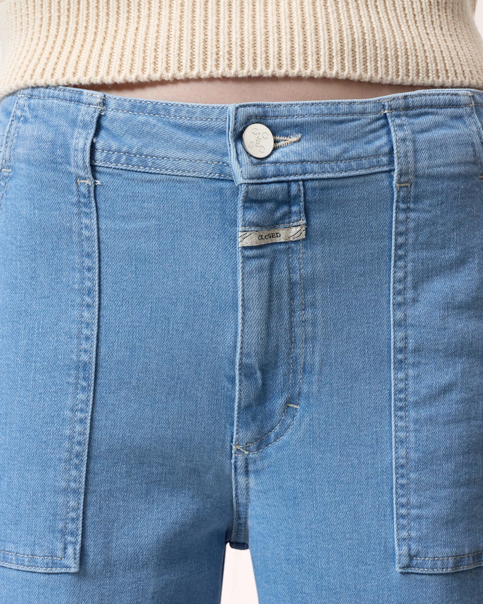 JONES + CO Aria flared jeans in light blue stretch denim with high waist, patch pockets, and wide belt loops.