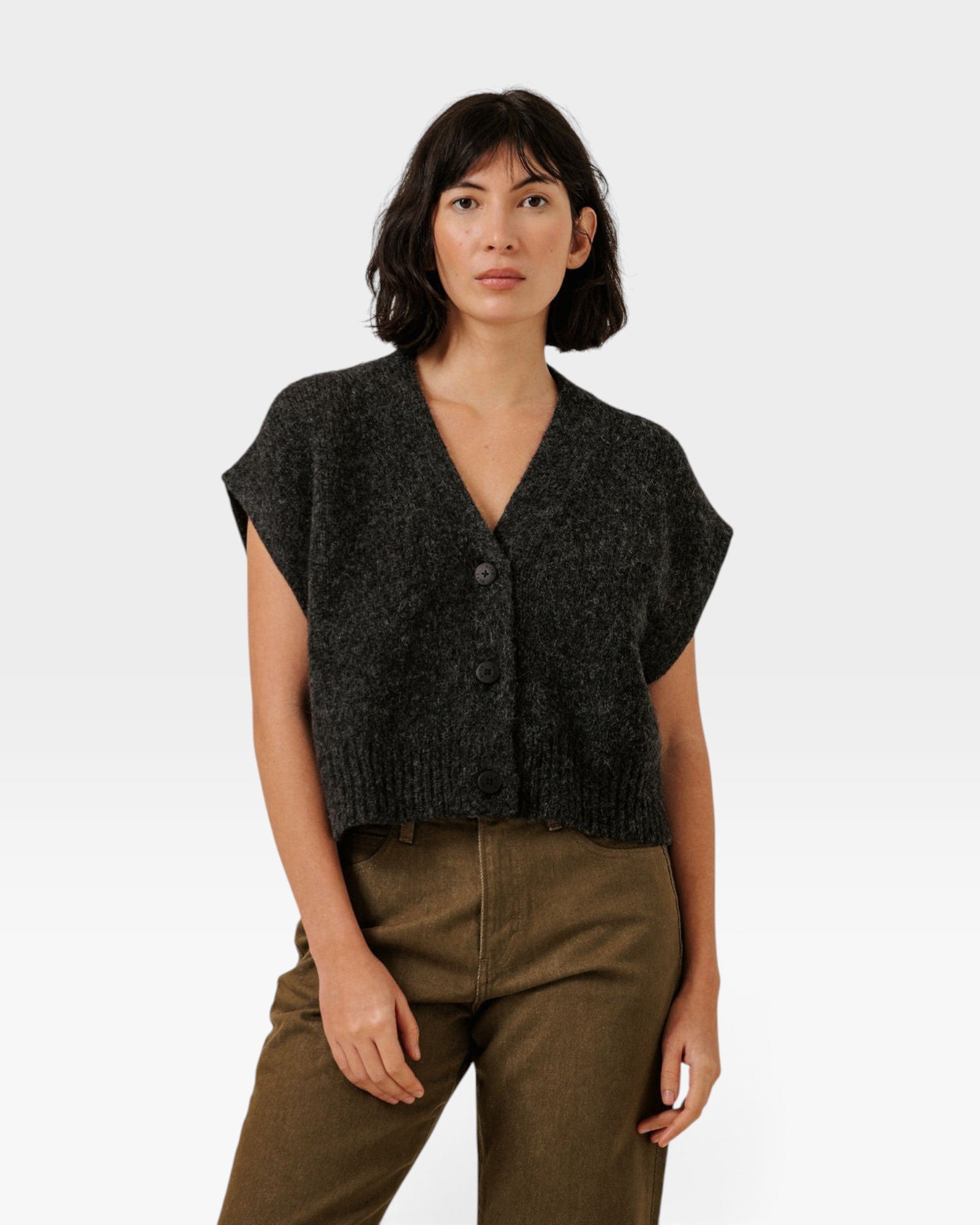 Model wearing a JONES + CO basalt grey cropped button-front vest in a soft alpaca and merino wool blend.