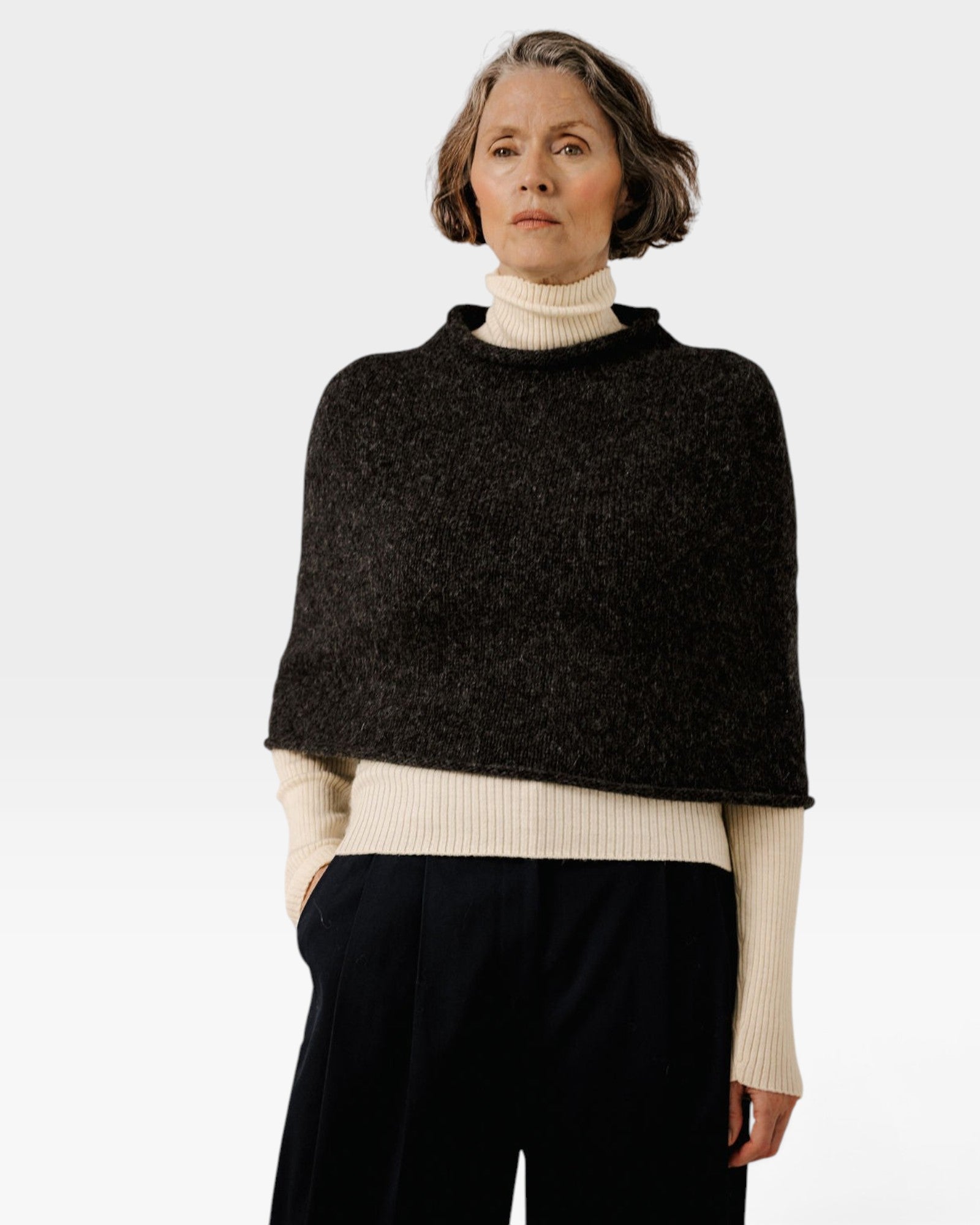 JONES + CO seamless alpaca-blend poncho in basalt grey worn over a cream turtleneck sweater