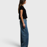 Model wearing JONES + CO black recycled cotton cropped V-neck t-shirt with wide-leg jeans, side profile view.