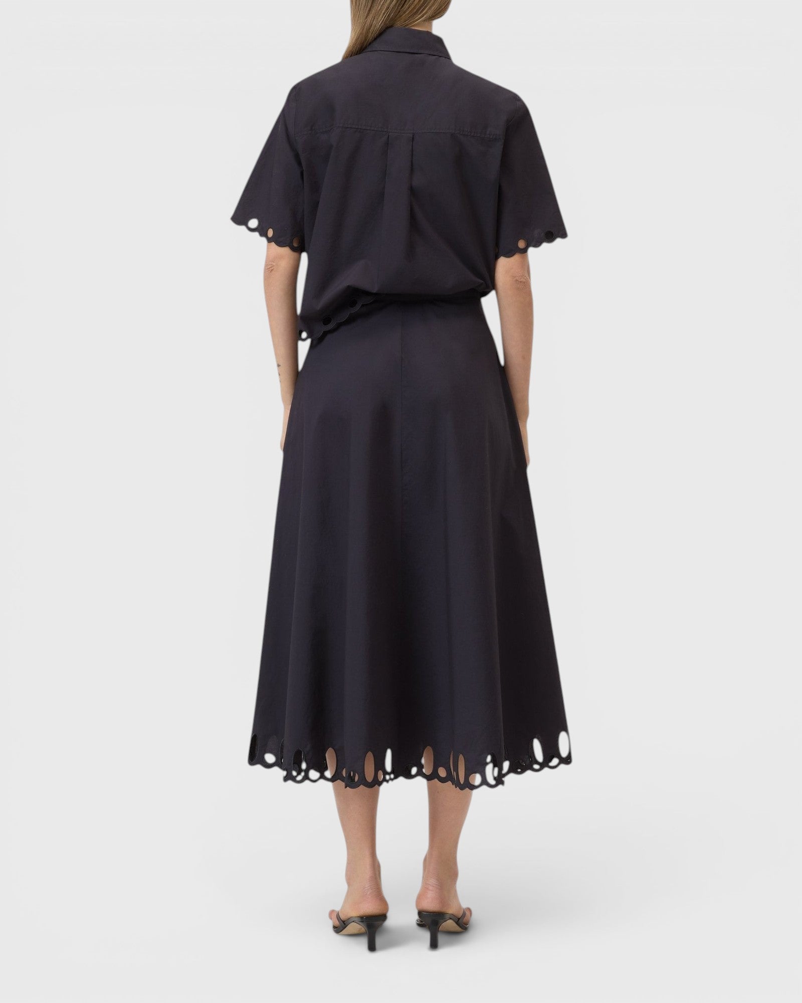 JONES + CO black midi skirt with cut-out embroidery hem, worn with matching short-sleeve shirt, back view