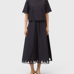 JONES + CO black midi skirt with flared silhouette and intricate cut-out embroidery along the hem on a model.