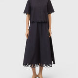 JONES + CO black midi skirt with flared silhouette and intricate cut-out embroidery along the hem on a model.