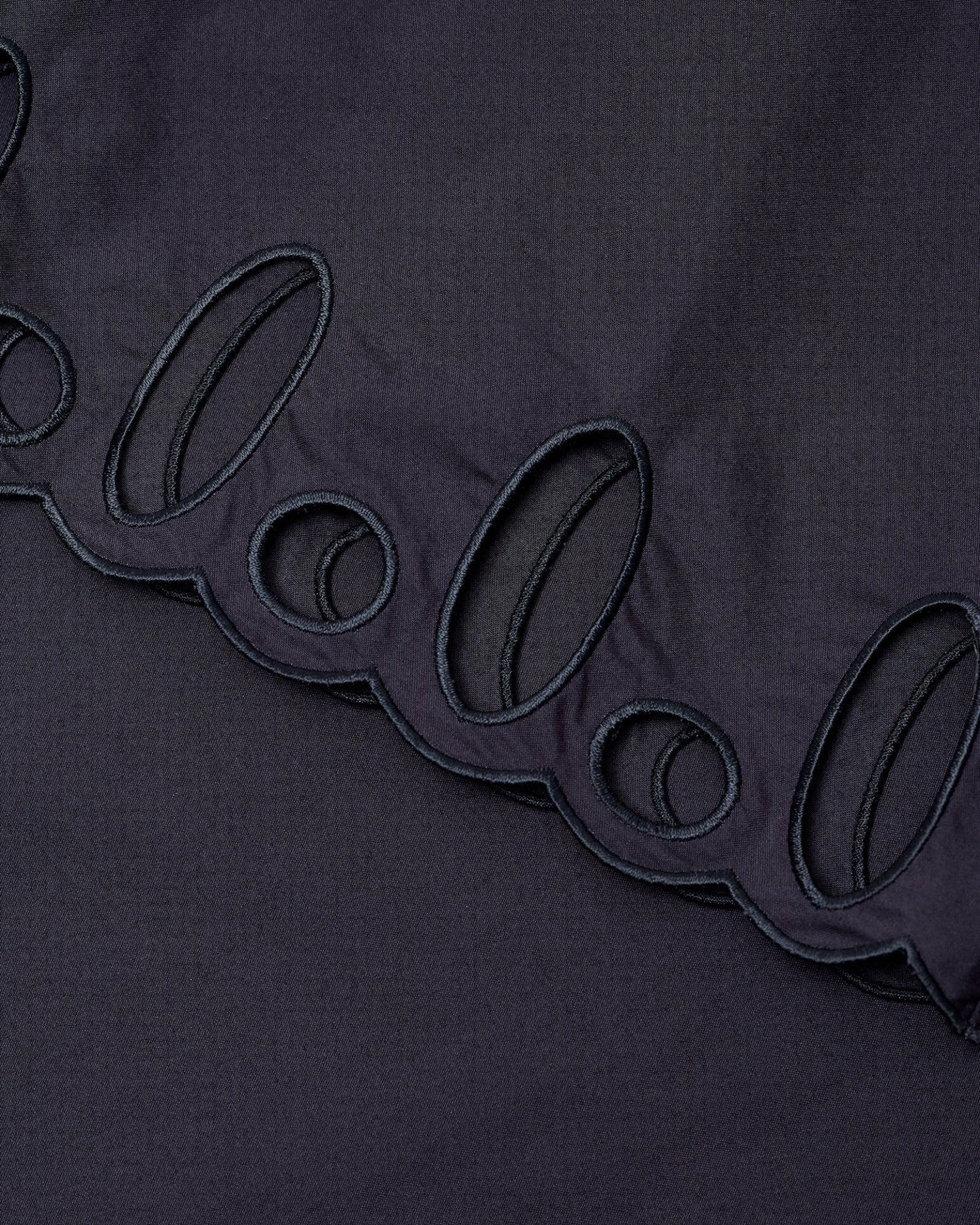 JONES + CO black midi skirt featuring intricate cut-out embroidery along the scalloped hemline.