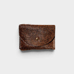 JONES + CO brown cowhide hair-on-hide cardholder with a solid brass fastener, front view.