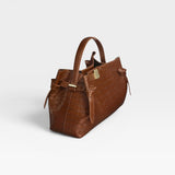 JONES + CO Gyoza pouch in brown embossed leather with a structured handle and gold hardware details.