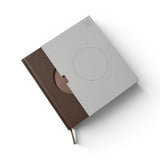 JONES + CO Open Journal with a brown fabric cover and light grey textured slipcase featuring a circular cutout.