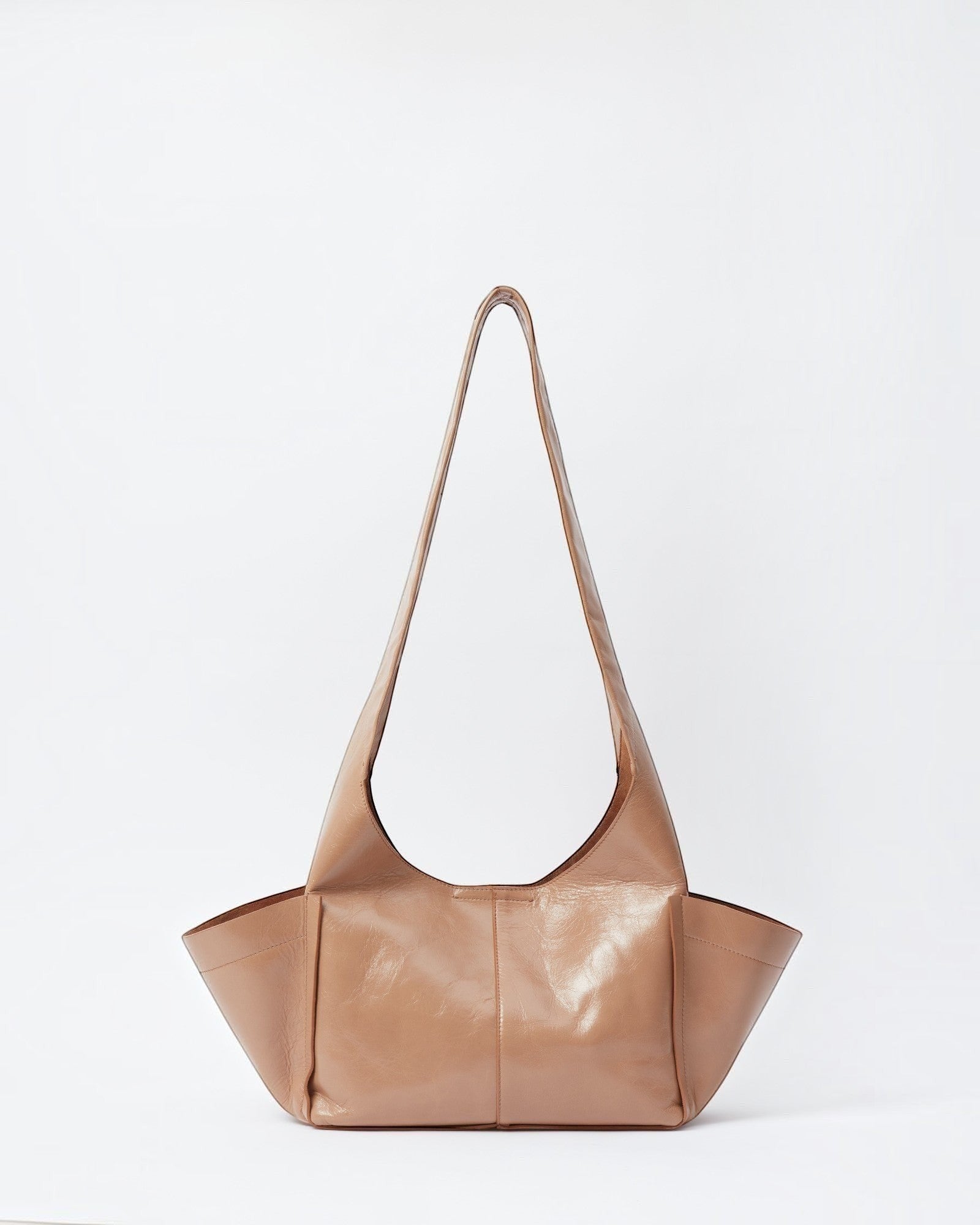 JONES + CO camel leather Tool Bag with a sculptural silhouette, fixed shoulder strap, and extended side pockets.