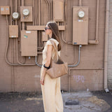 JONES + CO camel Tool Bag with shoulder strap and exterior pockets worn by a woman in a matching beige outfit.