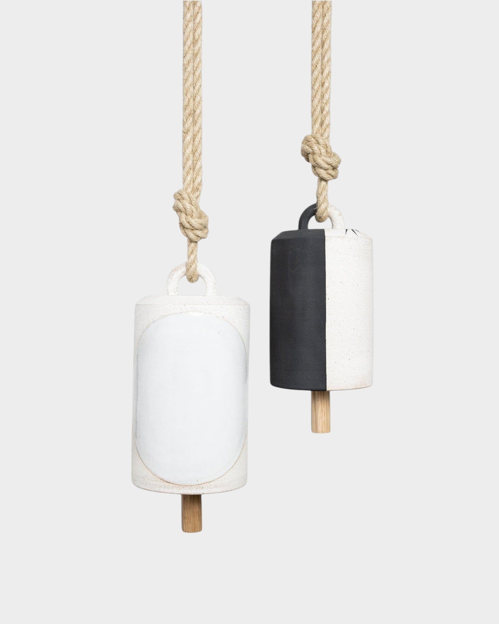 JONES + CO Thrown Bell Domino Indigo set featuring two ceramic bells with rope hangers in white and black finishes.