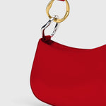 JONES + CO Ollie Bag in cherry-red polished leather with a crescent shape and mixed gold and silver strap hardware.