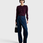 JONES + CO Chestnut lustre leather bucket bag with vertical paneling held by a model in a dark cardigan and jeans