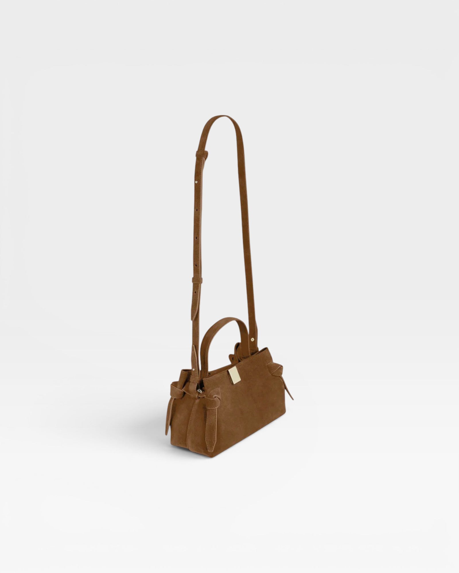 JONES + CO Gyoza Mini handbag in cognac suede with gold-tone hardware and adjustable shoulder strap, side view.