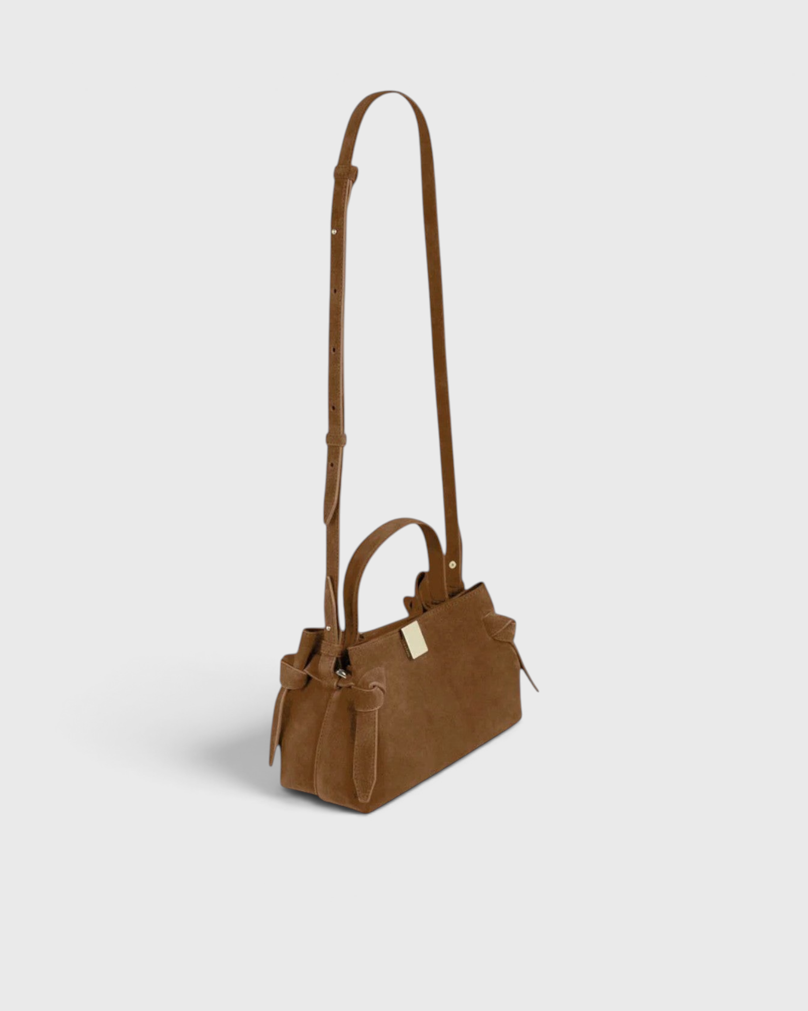 JONES + CO Gyoza Mini handbag in cognac suede with gold-tone hardware and adjustable shoulder strap, side view.