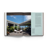 JONES + CO Courtyard Homes book open to a page showing a modern outdoor courtyard with white chairs and lush plants.