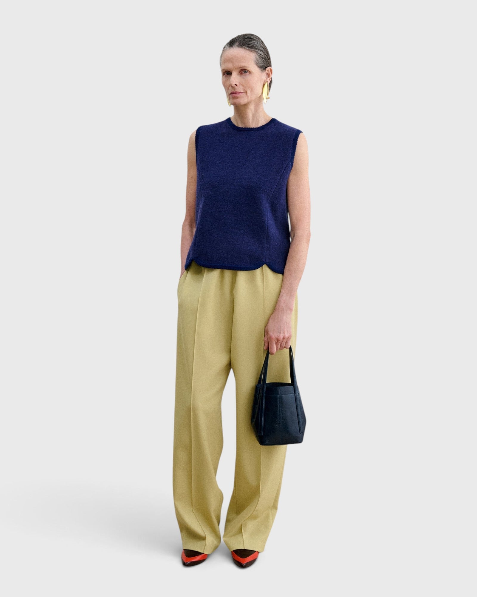 JONES + CO Bucket Tool bag in dark indigo lustre leather with vertical stitching, held by a model in a studio setting.