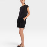 Model wearing a JONES + CO faded black boxy tank top in airy mesh stitch with refined trim and matching black shorts.