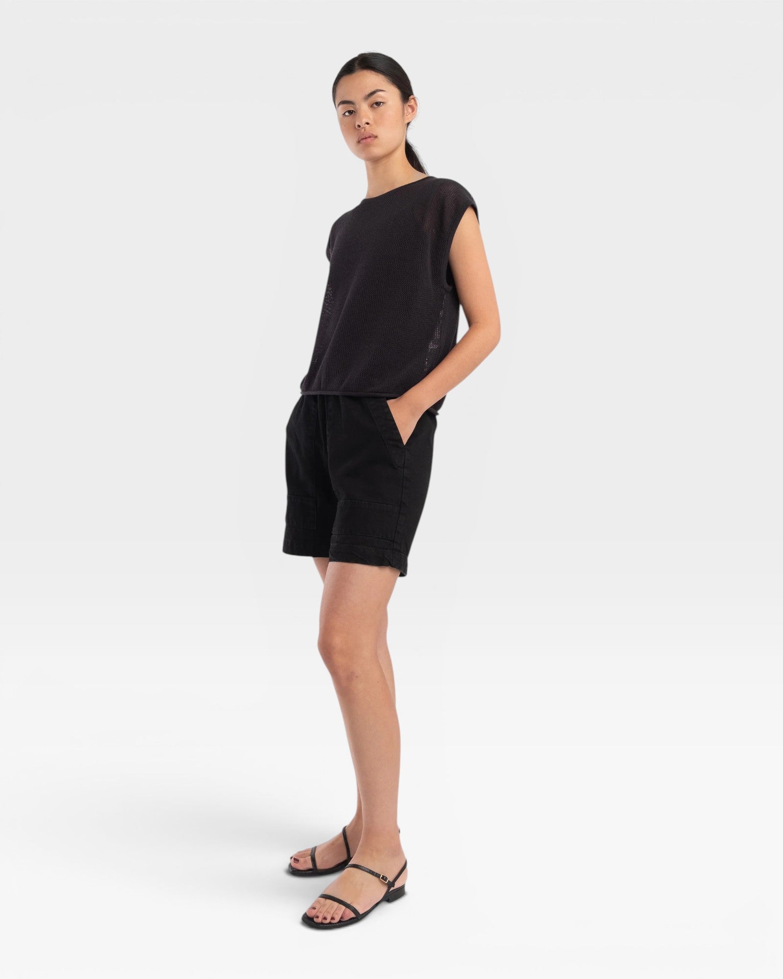 Model wearing a JONES + CO faded black boxy tank top in airy mesh stitch with refined trim and matching black shorts.