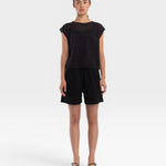 Model wearing a JONES + CO faded black boxy fine mesh tank top with refined trim details and matching black shorts.
