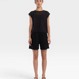 Model wearing a JONES + CO faded black boxy fine mesh tank top with refined trim details and matching black shorts.