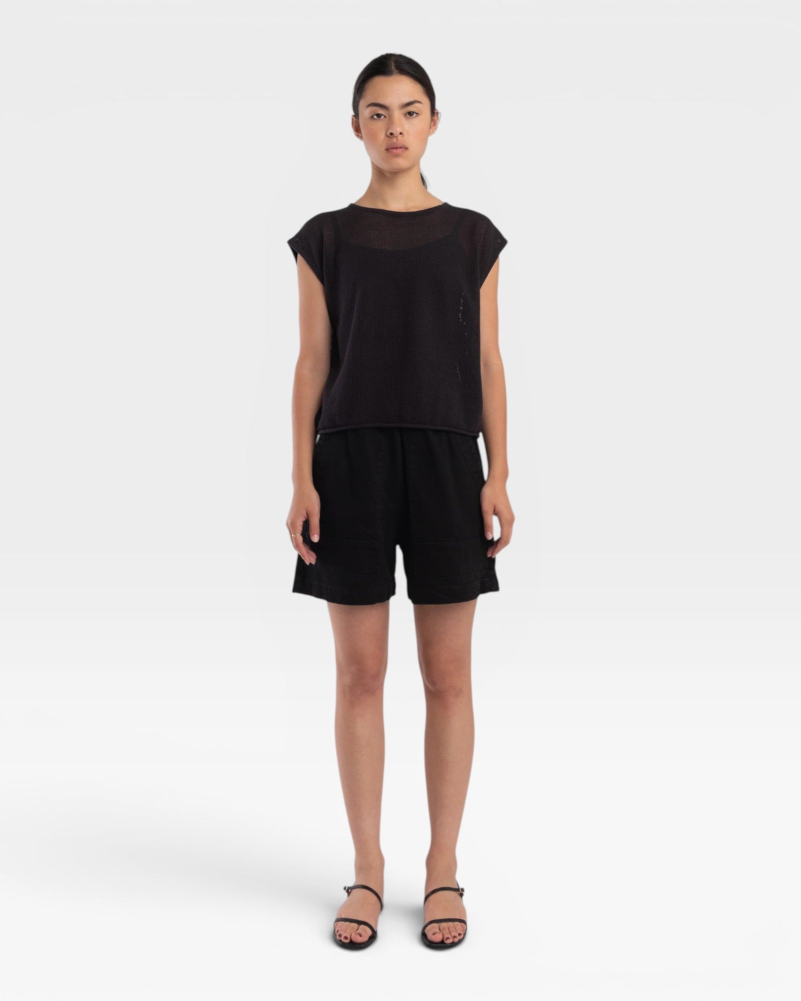 Model wearing a JONES + CO faded black boxy fine mesh tank top with refined trim details and matching black shorts.